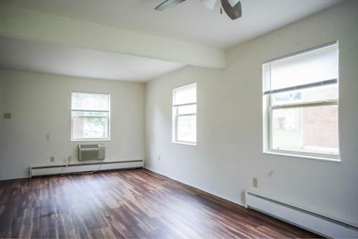 A room with a ceiling fan and two windows.
