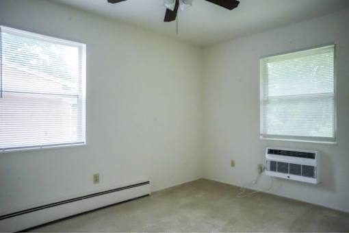 A room with a window and a fan on the ceiling.