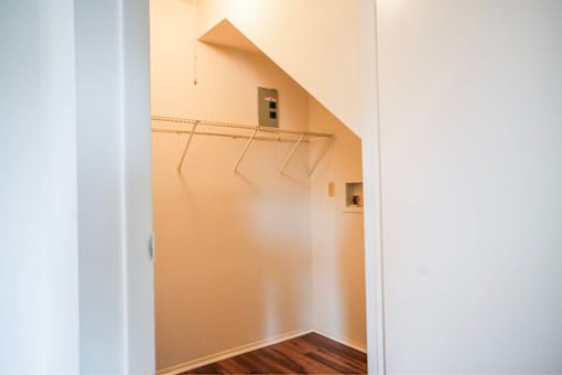 A white closet with a hanging rod and a white door.