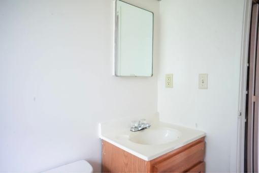 A white sink with a wooden cabinet and a mirror above it.