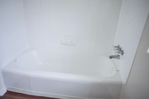 A white bathtub in a bathroom with a white wall.