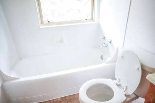 A white toilet is next to a bathtub in a bathroom.