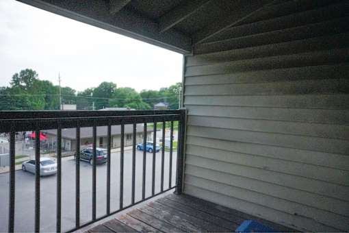 A balcony with a black railing overlooks a parking lot.