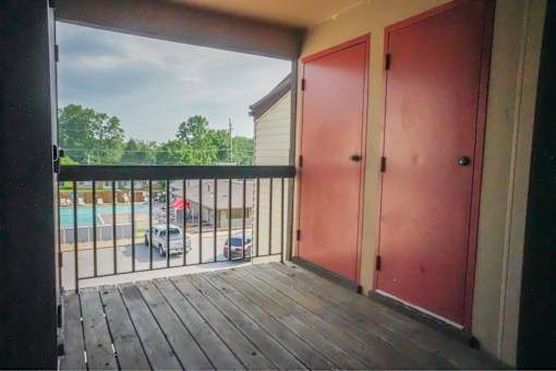 A balcony with a view of a parking lot and trees.