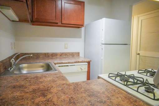A kitchen with a white refrigerator, a stove, and a sink.
