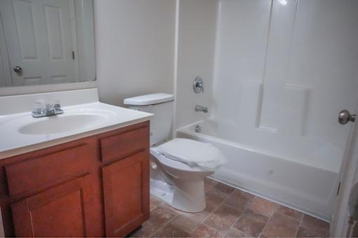 A white toilet sits in a bathroom next to a white sink.