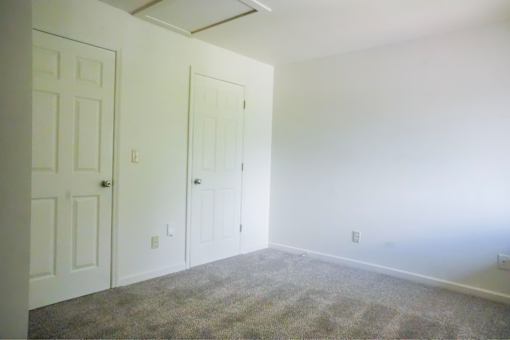 A room with two doors and carpeted floor.
