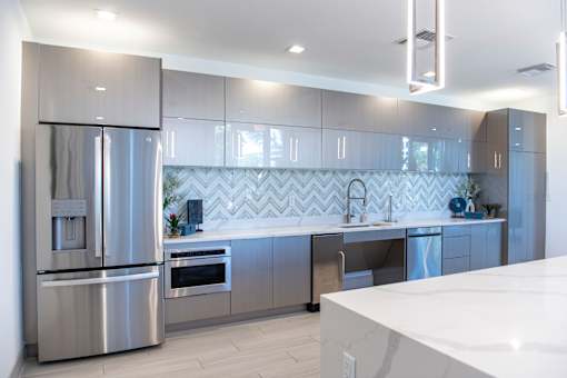A modern kitchen with a stainless steel refrigerator and a white countertop.