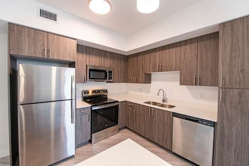 A modern kitchen with a stainless steel refrigerator and a microwave above the stove.