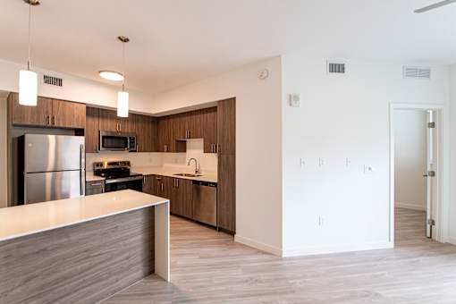 A modern kitchen with a refrigerator, microwave, oven, and sink.