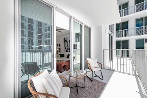 A balcony with a table and chairs overlooking a cityscape.