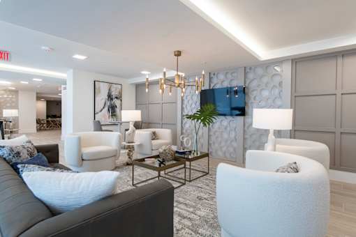 A modern living room with a grey sofa and white chairs.
