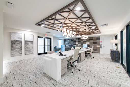 A modern office with a white desk and chairs, a wooden ceiling, and a tiled floor.