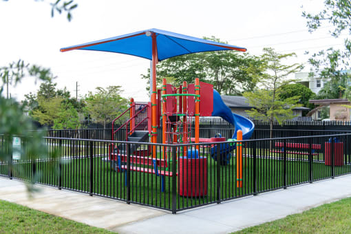 a playground is shown behind a black wrought iron fence