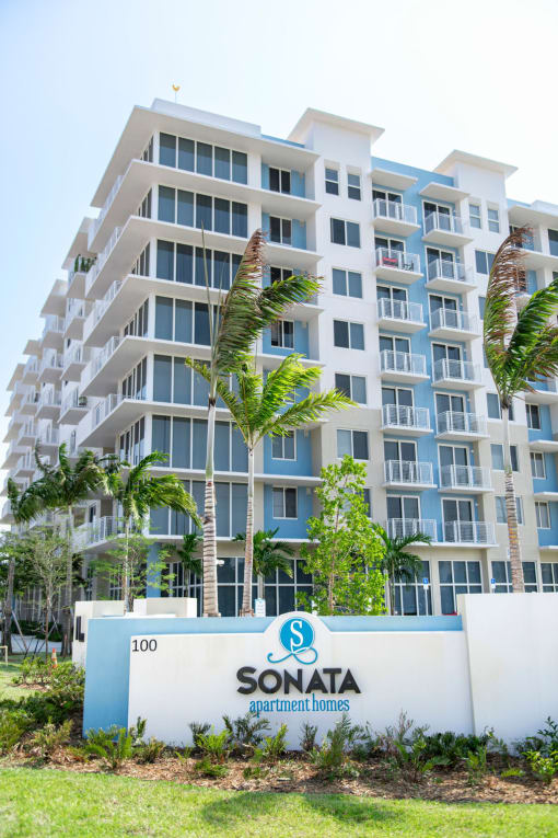 a view of a condo building with palm trees in front of it