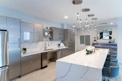 a large white kitchen with stainless steel appliances and a marble counter top