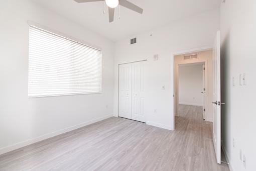 A room with a ceiling fan and a door leading to another room.