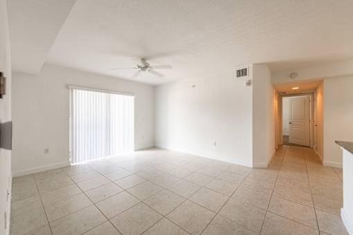 A spacious room with a ceiling fan and a doorway leading to another room.