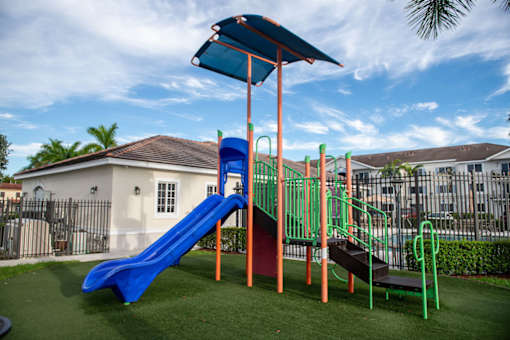 A playground with a blue slide and a green and orange structure.