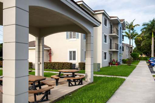 A row of apartment buildings with a covered picnic area in front.