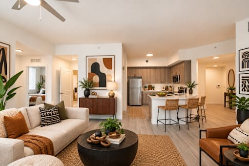 A modern living room with a white sofa, a coffee table, and a dining area in the background.