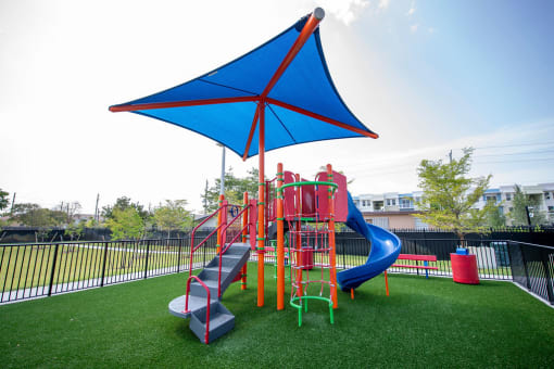 a playground with a blue umbrella and colorful playset