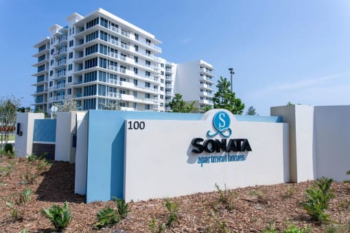 a sign in front of a building with condos in the background