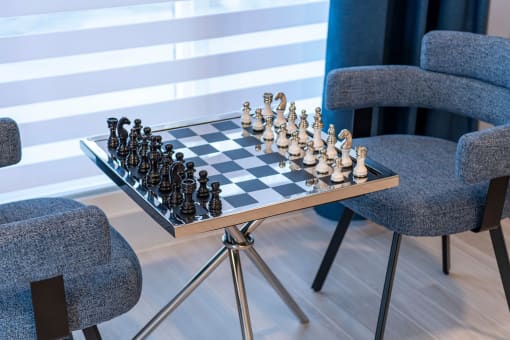 a chess board on a table in a room with chairs