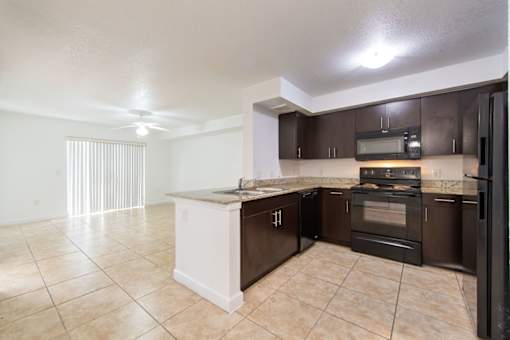A kitchen with brown cabinets and black appliances.