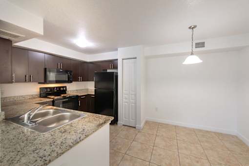 A kitchen with granite countertops and a black refrigerator.