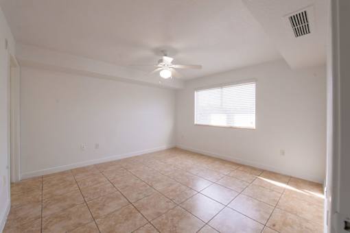 A room with a ceiling fan and a window with blinds.
