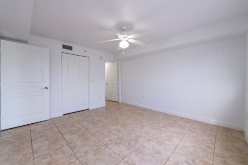 A room with a ceiling fan and tile flooring.