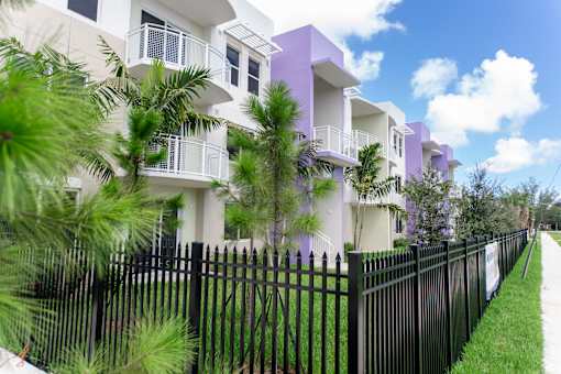 A row of houses with a black fence in front.