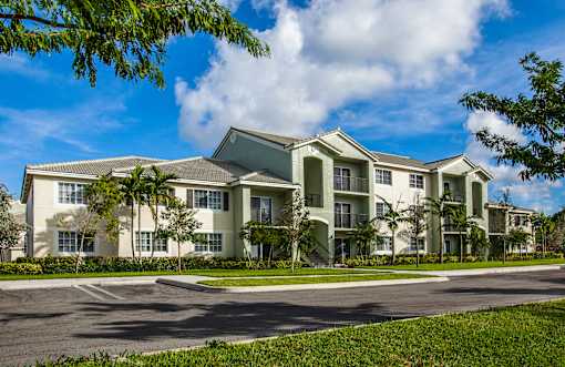 A large, modern apartment building with a parking lot in front.