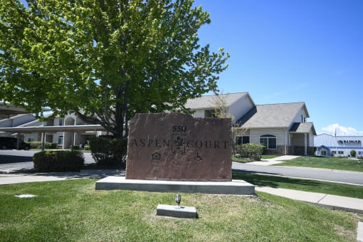 a stone sign sitting in the grass in front of some houses