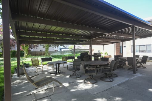 a patio with tables and chairs under awning