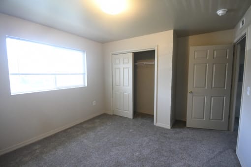 an empty living room with two doors and a window