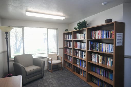 a library with two chairs and a large book shelf