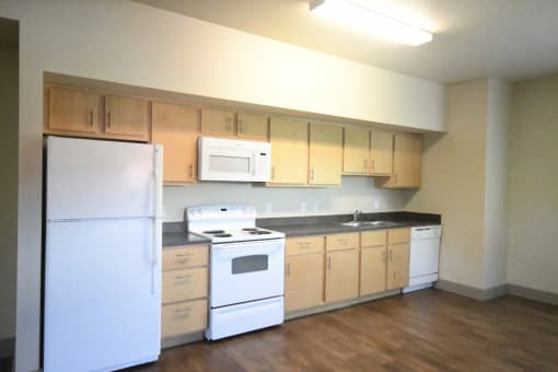 an empty kitchen with white appliances and wooden cabinets