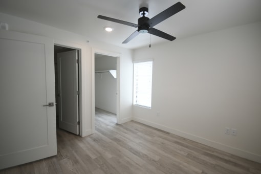 a living room with white walls and a ceiling fan