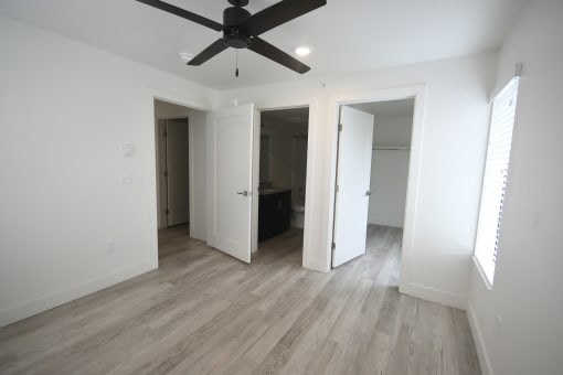 an empty living room with white walls and a ceiling fan