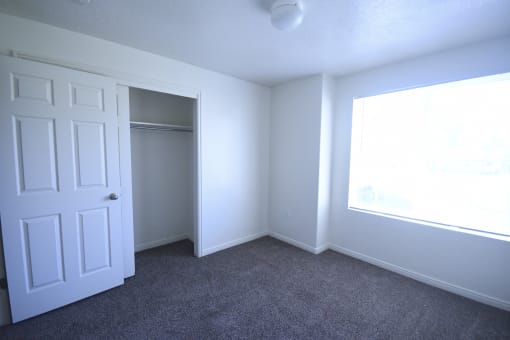 an empty bedroom with a closet and a window