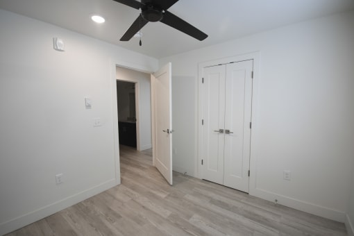 a bedroom with white walls and a ceiling fan