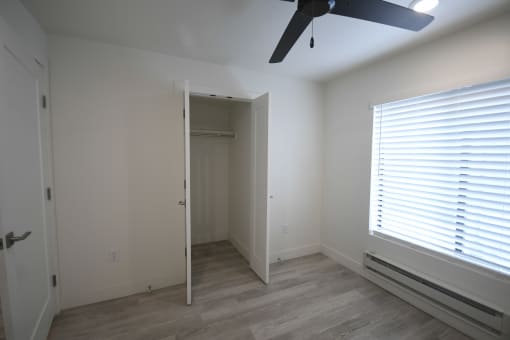 a bedroom with a large window and a ceiling fan