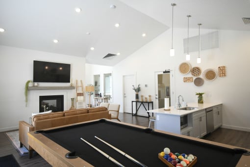 a living room with a pool table and a kitchen