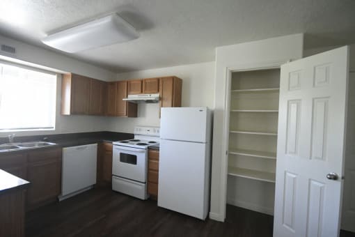 an empty kitchen with white appliances and wooden cabinets