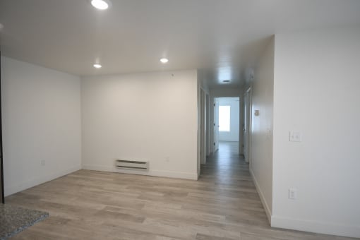 a living room and hallway with white walls and wood flooring
