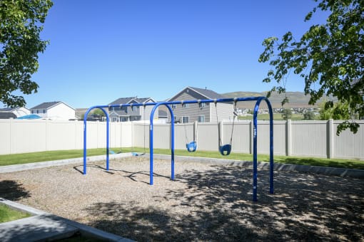 a blue swing set in a park with houses in the background