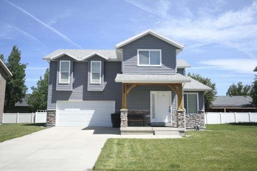 a blue house with a white garage door and a lawn