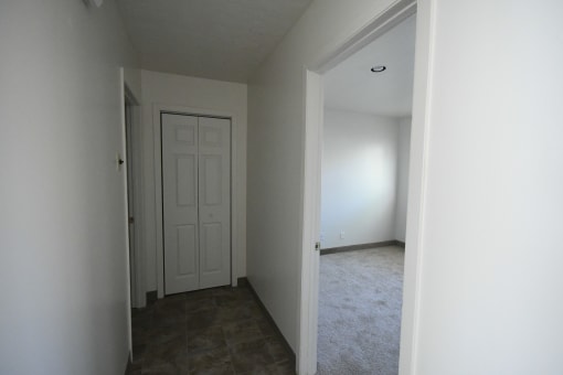 an empty room with a white door and a hallway with a door to a closet